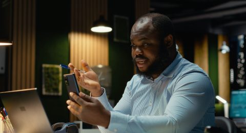 Businessman interacting with staff during video conference on smartphone