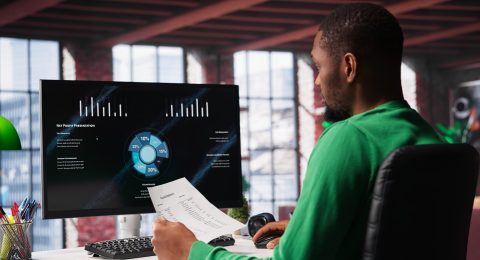 Black freelancer at home watching business conference on PC monitor